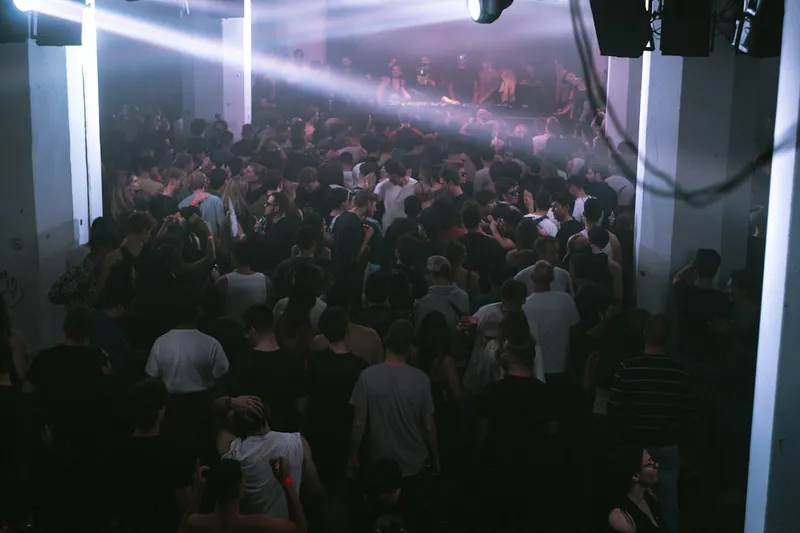 Crowded nightclub with bright spotlights illuminating dancers