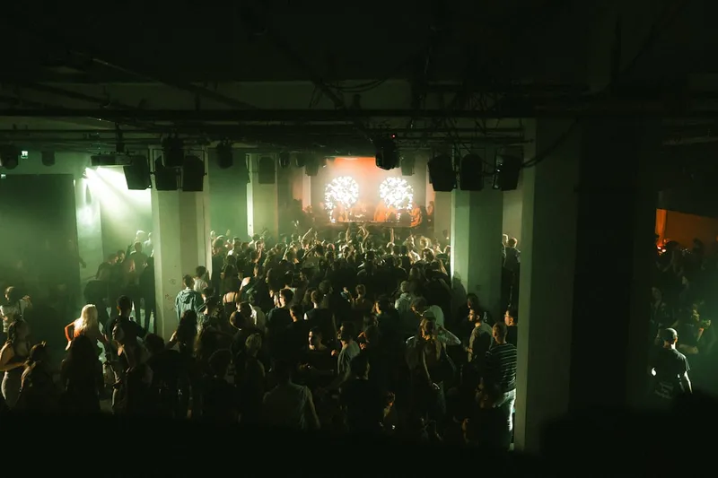Crowd dancing in a dimly lit club with stage lights